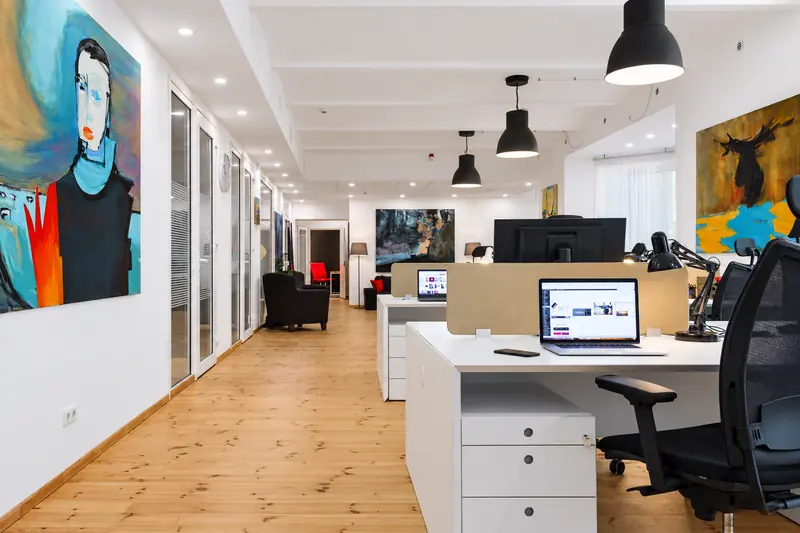 Coworking Riga kopstrādes telpa ar darba galdiem un gleznām