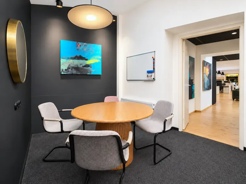 Coworking Riga sapulču telpa ar apaļu galdu un melnu sienu